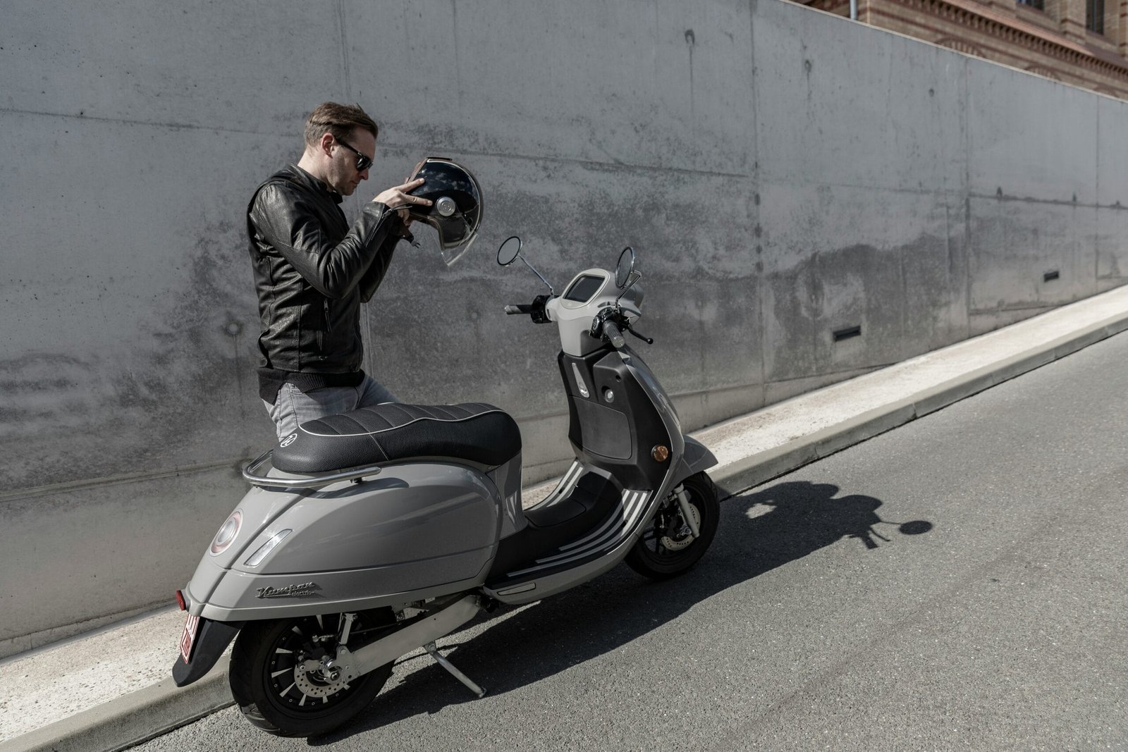 man in black jacket riding on gray motor scooter